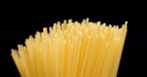 Bunch of Raw Spaghetti Rotating Against Black Background