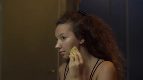 Woman Applies Makeup with Sponge in Bathroom