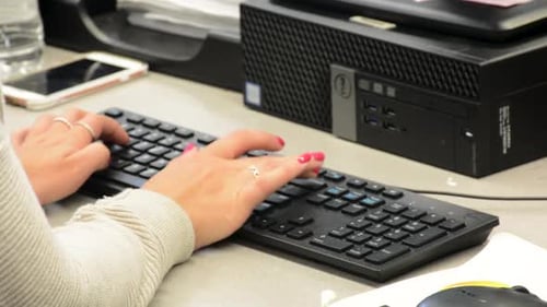 Close up of woman’s hands while typing on computer keyboard wearing a sweater