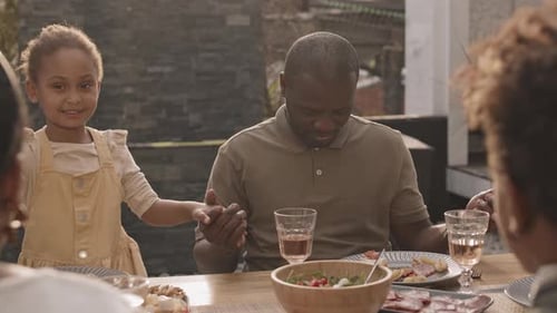 Family Joins Hands for Mealtime Prayer Outside