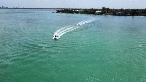 Flying over the ocean with a beach in the background. As the camera passes over the water several bo