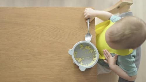 Infant Eating Food with Hands in High Chair