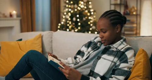 Woman Reads Book on Couch at Christmas Time