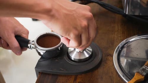 Barista préparant le café à presser, à tempérer sur un porte-filtre avant de le préparer avec une machine au café