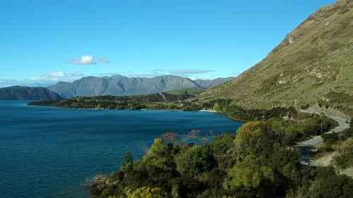 aerial shot of Lake Wanaka with a car drives on a road on the right side