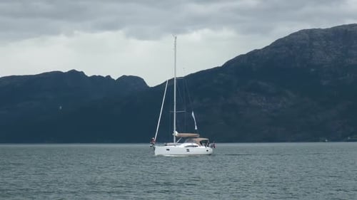 Un yacht avec des voiles baissées Voiles sur fond de montagnes sombres