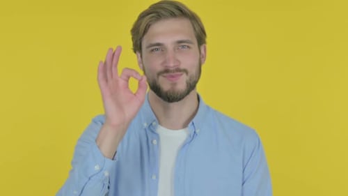 Smiling Man Gives Okay Hand Gesture on Yellow