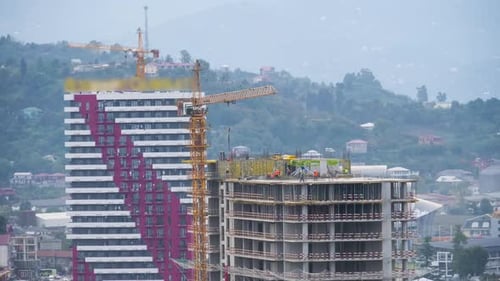 Hochbau. Zeitraffer. Turmdrehkran auf einer Baustelle hebt eine Last am Hochhaus