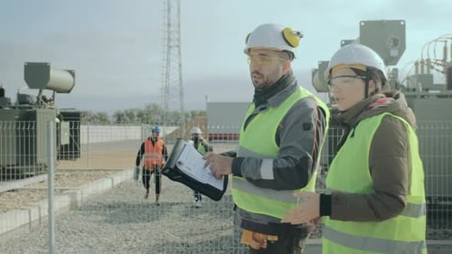 Power Engineers Walk Along the Transformers and Discuss the Construction Project.