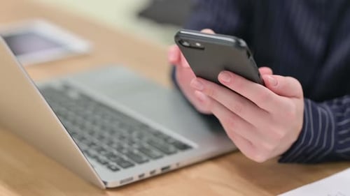 Close Up of Man Using Smartphone and Laptop