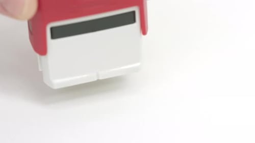 Red Rubber Stamp Presses Failed onto White Surface