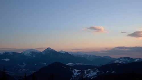landscape with mountains and forests at dusk, clear sky with small clouds. End of the day