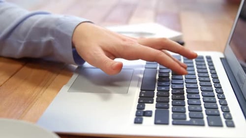 Hand Typing on Laptop Keyboard at Desk