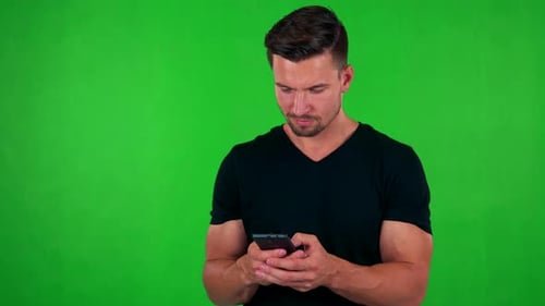 Young Handsome Caucasian Man Works (Typing) on Smartphone - Green Screen