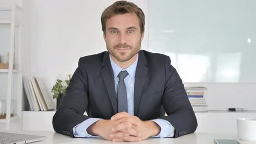 Confident Business Man in Suit Sitting at Desk