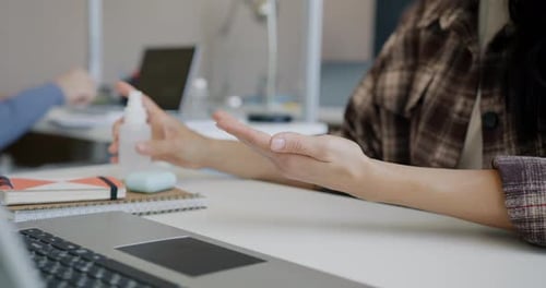 Closeup of Woman Cleaning Hands with Sanitizer Then Working with Laptop in Office