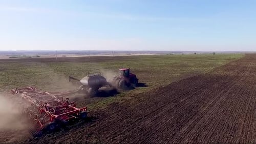 Aerial view of Tractor plow in a huge field. Summer, sunny day.