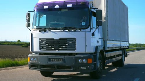 Camera Follows To Truck with Cargo Trailer Driving on Highway and Transporting Goods at Summer Day