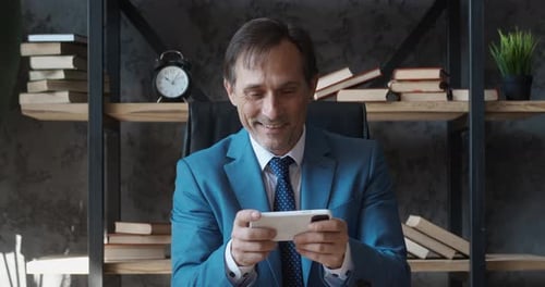 Man in suit celebrates while playing mobile game