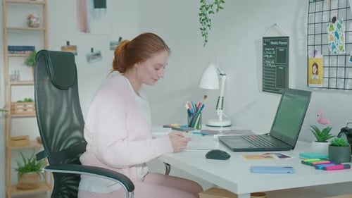 Woman Working on Laptop and Writing Notes