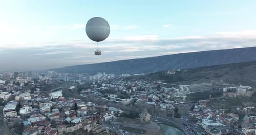 Flying over white balloon in the center of city. Sunset cityscape of Tbilisi, Georgia 2022
