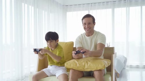 Dad and Son Play Video Games Together at Home
