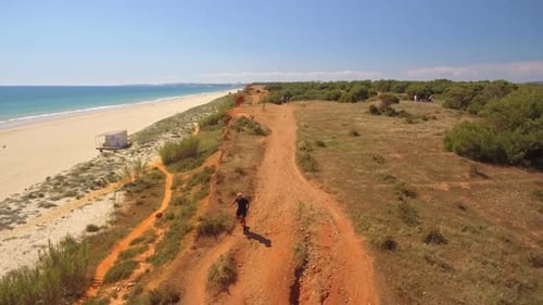 Aerial View of an Elderly Man Running Along the Ocean Coast