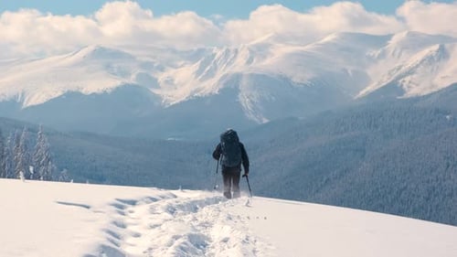 Man Backpacker Hiking Snowy Mountain Hillside on Cold Winter Day