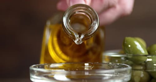 Male Hand Pouring Olive Oil From a Jug Into a Bowl.
