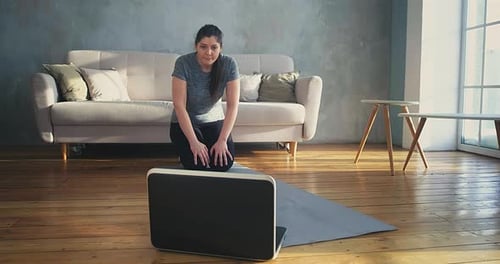 Woman Works Out at Home Using Laptop