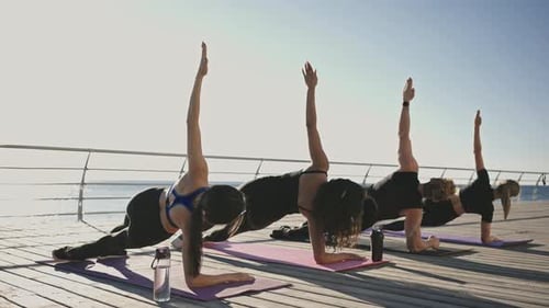 Women Practicing Yoga on a Beach Boardwalk