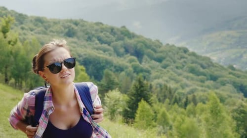 A Very Tired Woman Tourist with a Backpack Goes Up the Mountain Path