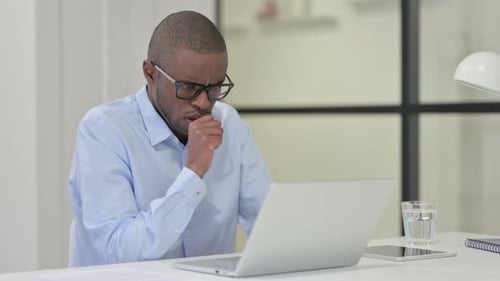 Adult Coughs While Working at Laptop in Office