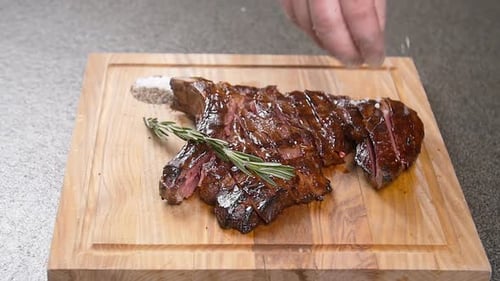 Juicy Steak Sliced and Garnished on Wooden Board