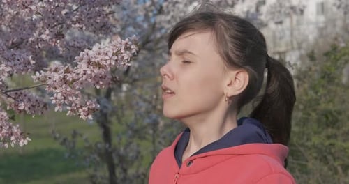 Girl Sneezing Near Blossoming Tree in Springtime