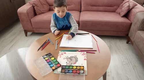 Young Boy Drawing With Pencils at Home