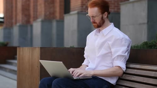 Designer Typing on Laptop while Sitting Outside Office