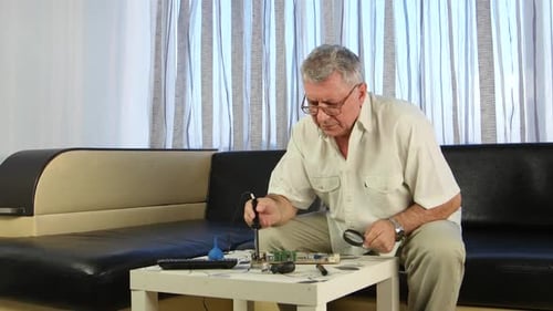 Man Carefully Repairs Electronic Component at Home