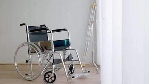 Empty modern wheelchair and walking stick or canes in hospital room.