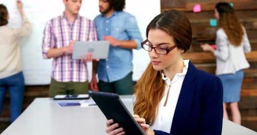 Businesswoman Smiling While Using Tablet in Office