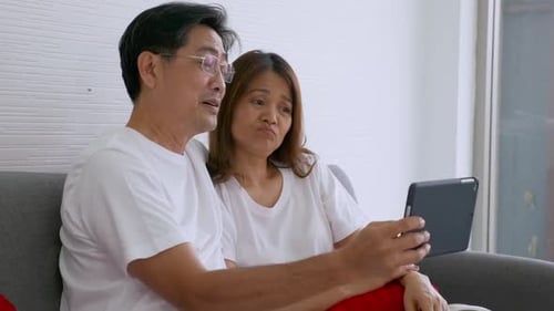 Happy Couple Video Calling with a Tablet Indoors