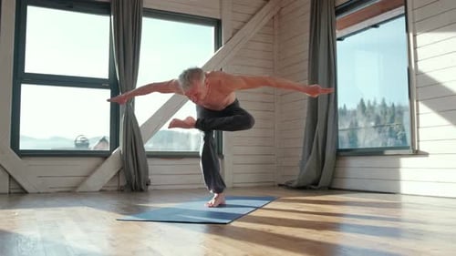 Man Practices Yoga Balancing Pose Indoors