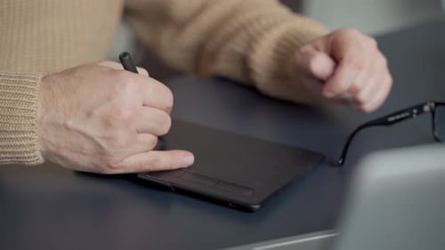 Man Uses Graphics Tablet and Stylus at Desk