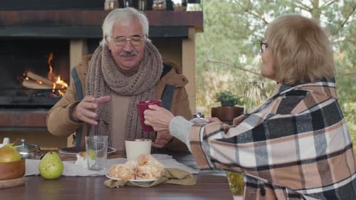 Aged Couple Drinking Tea on Outdoor Terrace