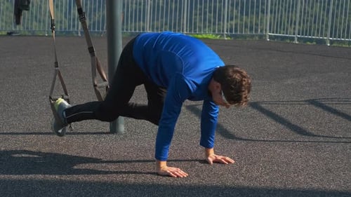 Entraînement en plein air d'un sportif avec des sangles TRX