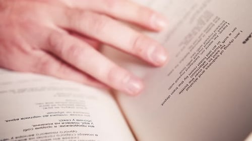 Handumblättern eines Buches, NAHAUFNAHME. ZEITLUPE. Die Hand einer nicht wiederzuerkennenden Person beim Lesen eines Buches und
