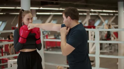Woman Boxing with Trainer Inside Ring at Gym