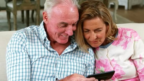 Senior Couple Looking at Phone Together on Couch