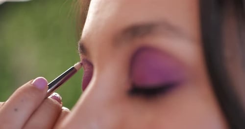 Woman getting eye makeup applied with brush