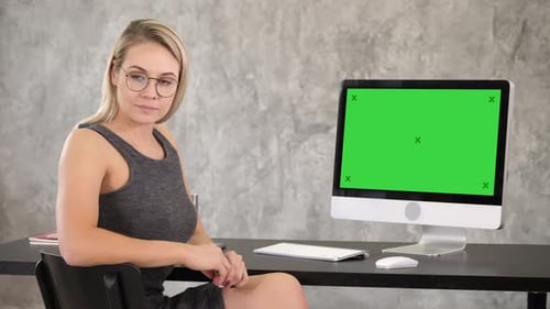 Woman at Desk in front of Computer Green Screen